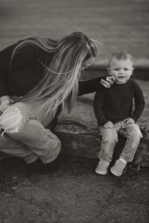 Black and white portrait of parent and child sharing a moment on stone steps.