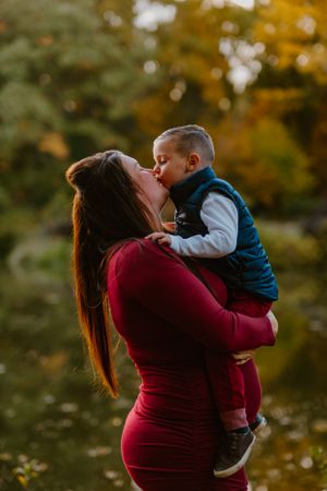 A tender moment between parent and child captured in autumn with golden bokeh and a burgundy dress.