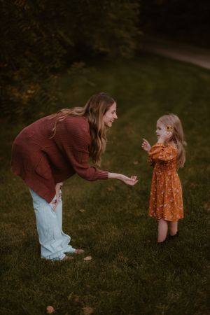 A playful interaction between two people on a grassy lawn during golden hour.