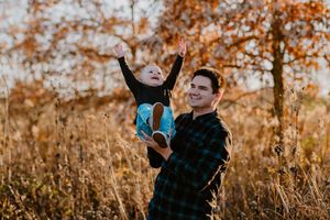 A playful autumn photoshoot in a field with warm golden light and tall grass in the background.