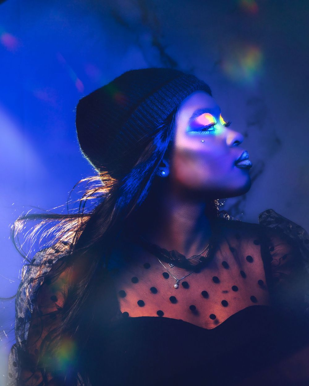 Artistic portrait with neon lighting and beanie hat in dark atmospheric setting.