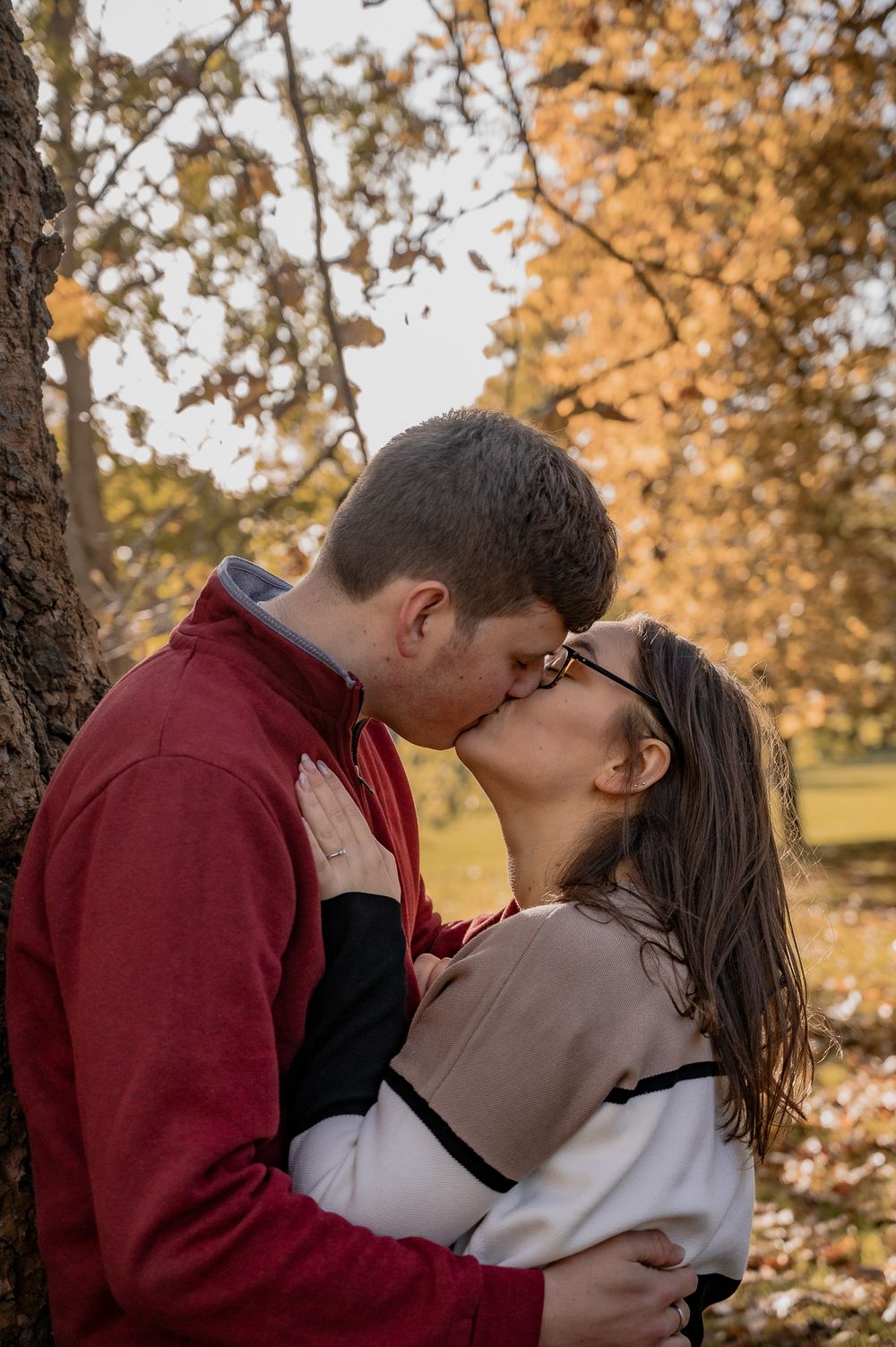 A romantic autumn scene with a couple sharing an intimate moment under fall foliage.
