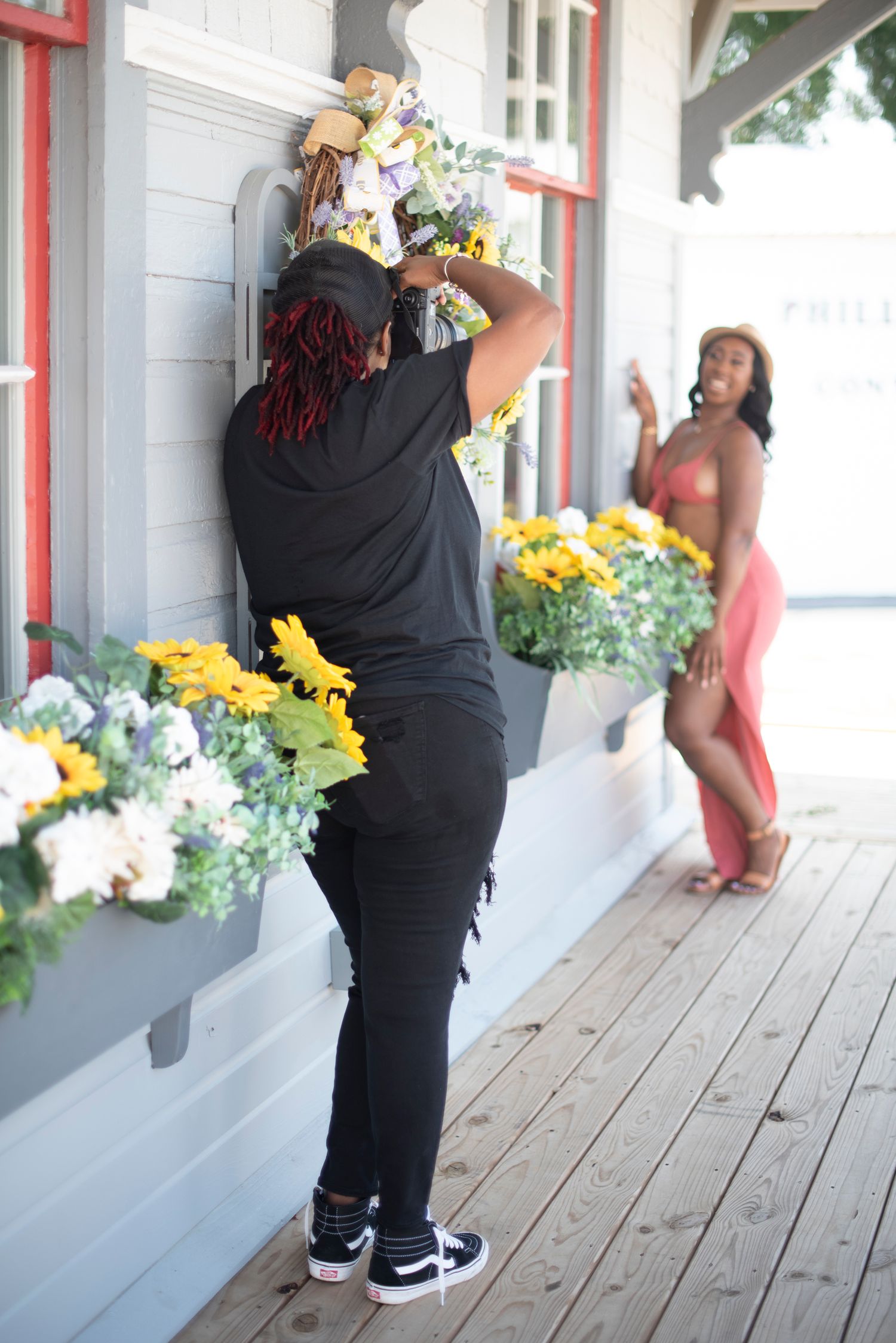 Casual photoshoot on wooden porch with yellow flowers and white railings.