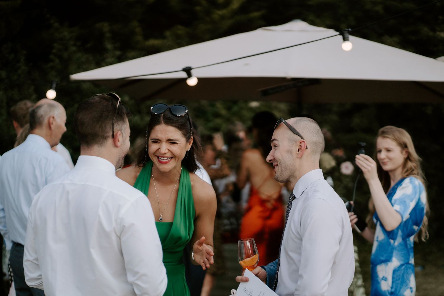 wedding guests talking and laughing with each other on lawn in islip, Oxfordshire