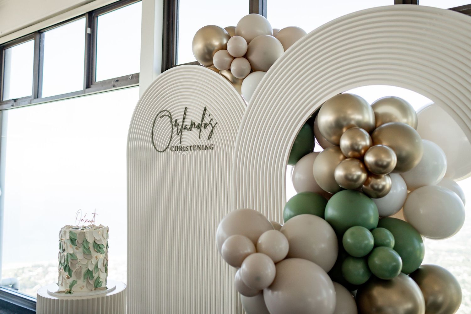 Modern event decor featuring an arched balloon installation in neutral tones with metallic accents.