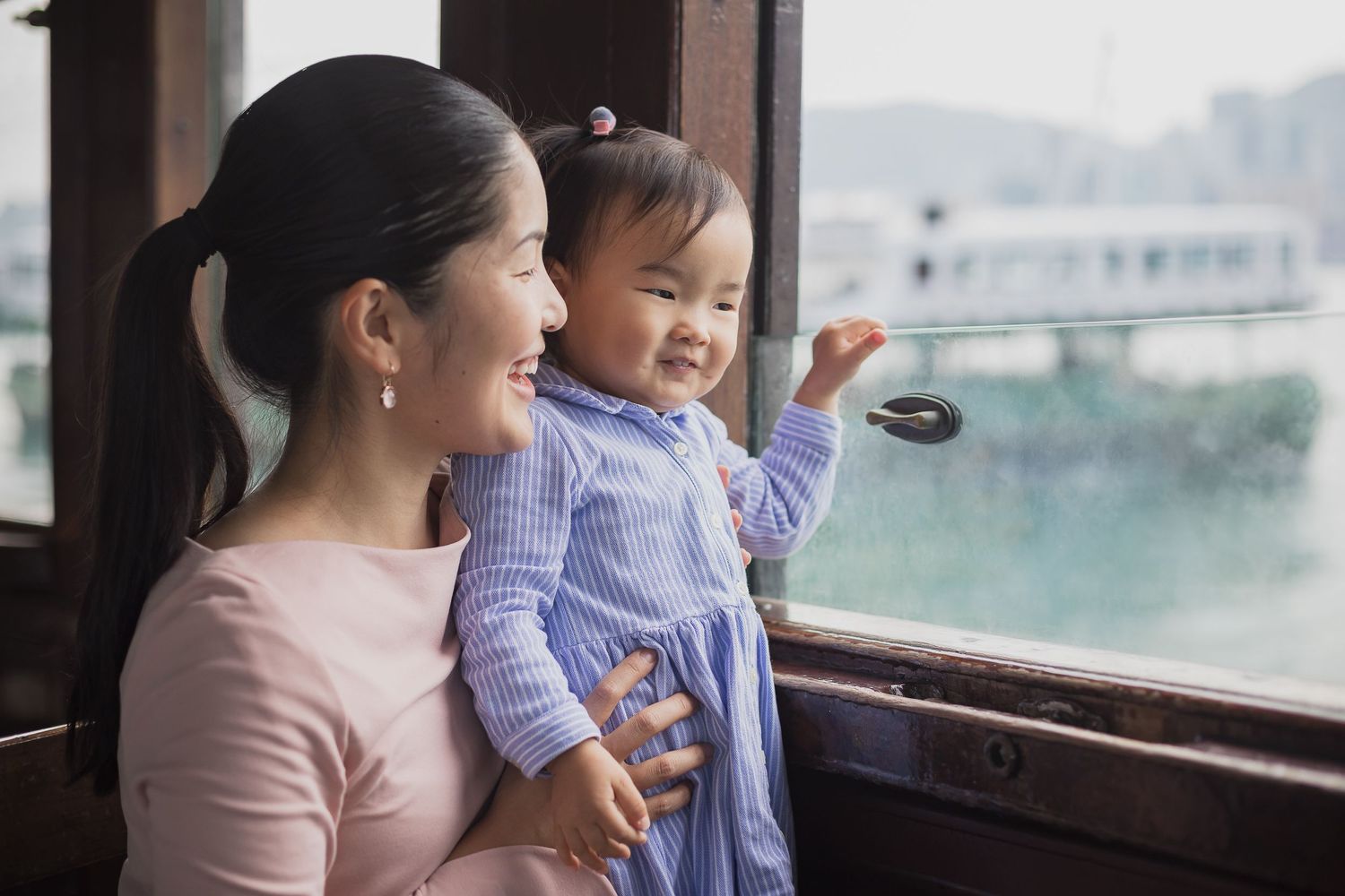 Parent and child sharing a joyful moment while looking out window together.