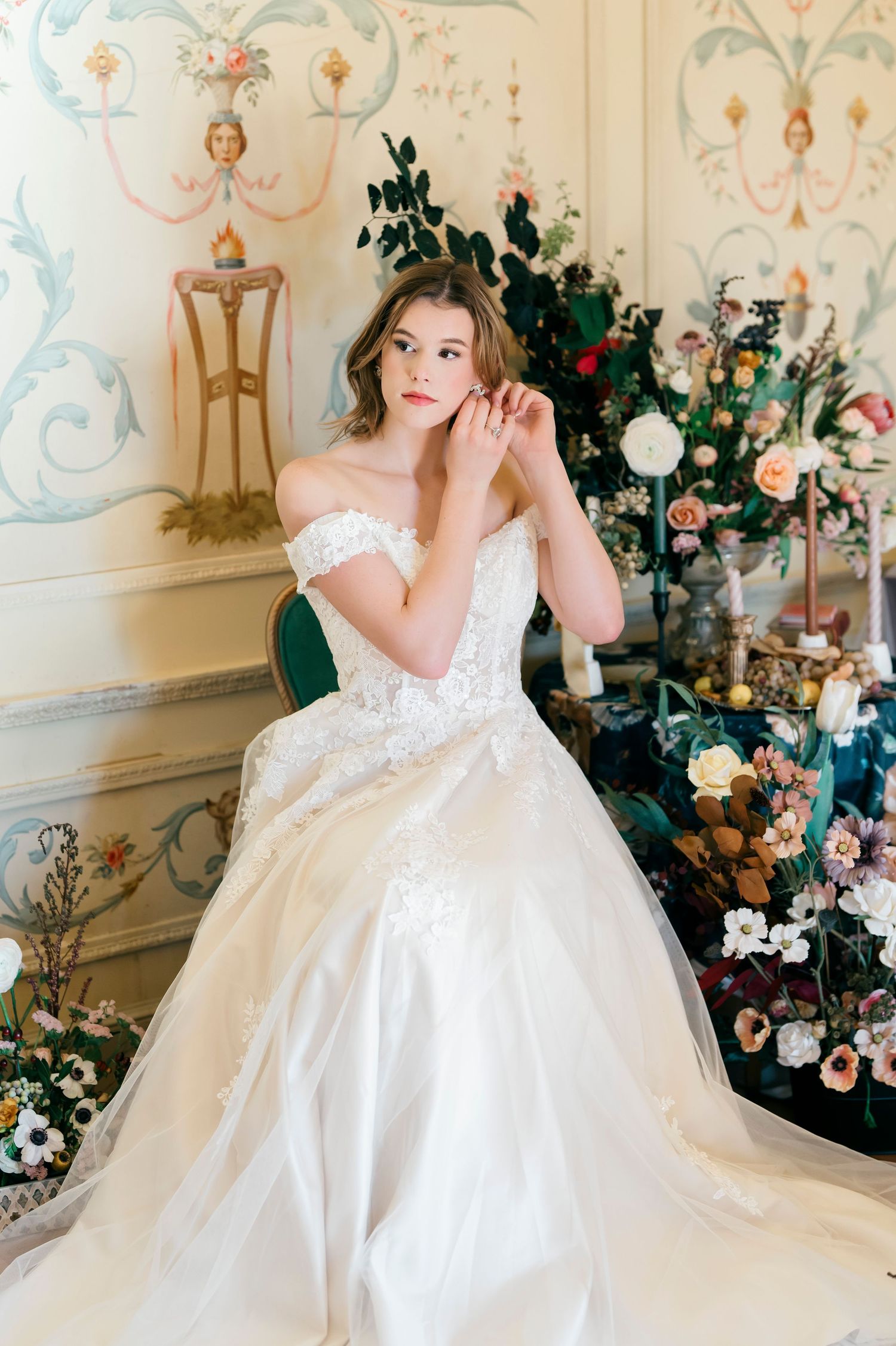 Romantic bridal portrait in an ornate room with floral arrangements and painted wall details.