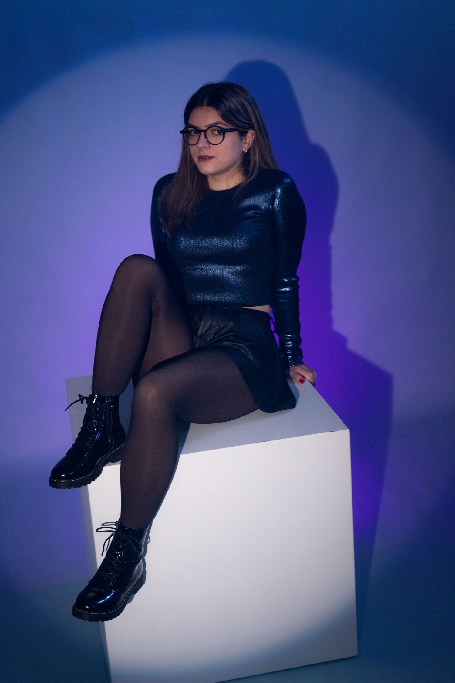 Artistic portrait on white pedestal with dark clothing and dramatic lighting.