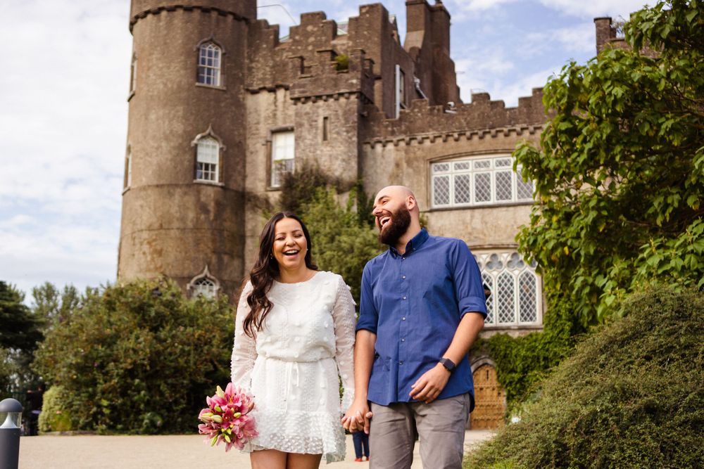 bride to be at malahide castle laughing and holding hands with her fiancé