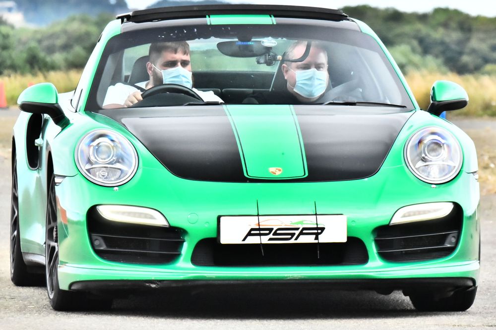 Green and black Porsche sports car with white racing stripes.