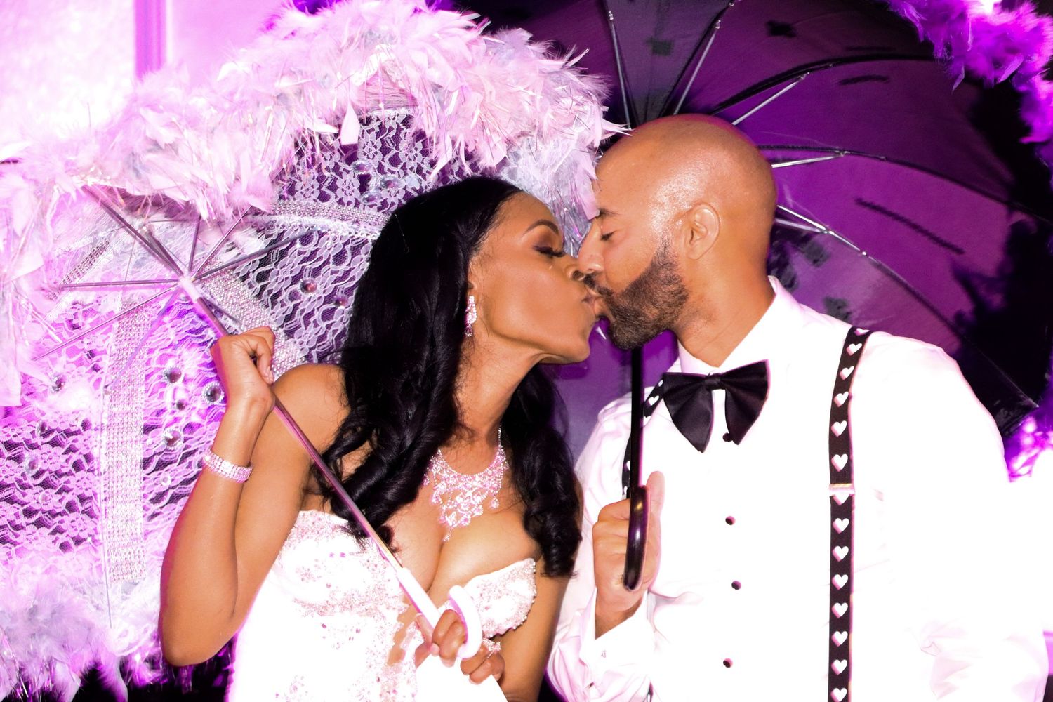 Couple shares intimate moment under purple lighting with decorative umbrellas.