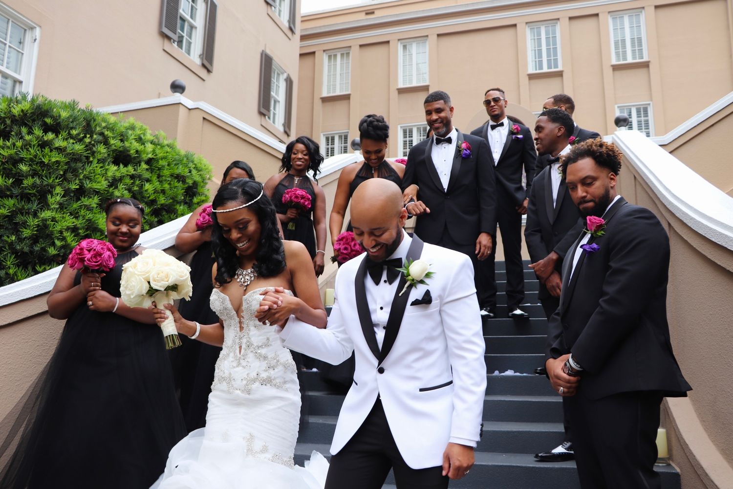 Wedding party poses on outdoor staircase with bridesmaids and groomsmen.