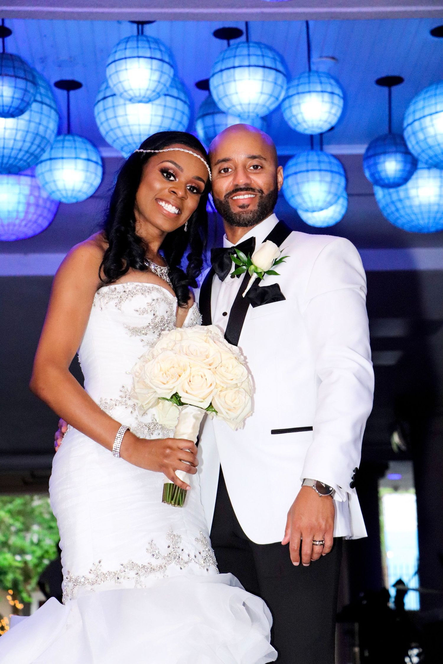 Wedding portrait under blue disco ball lighting with white floral bouquet.