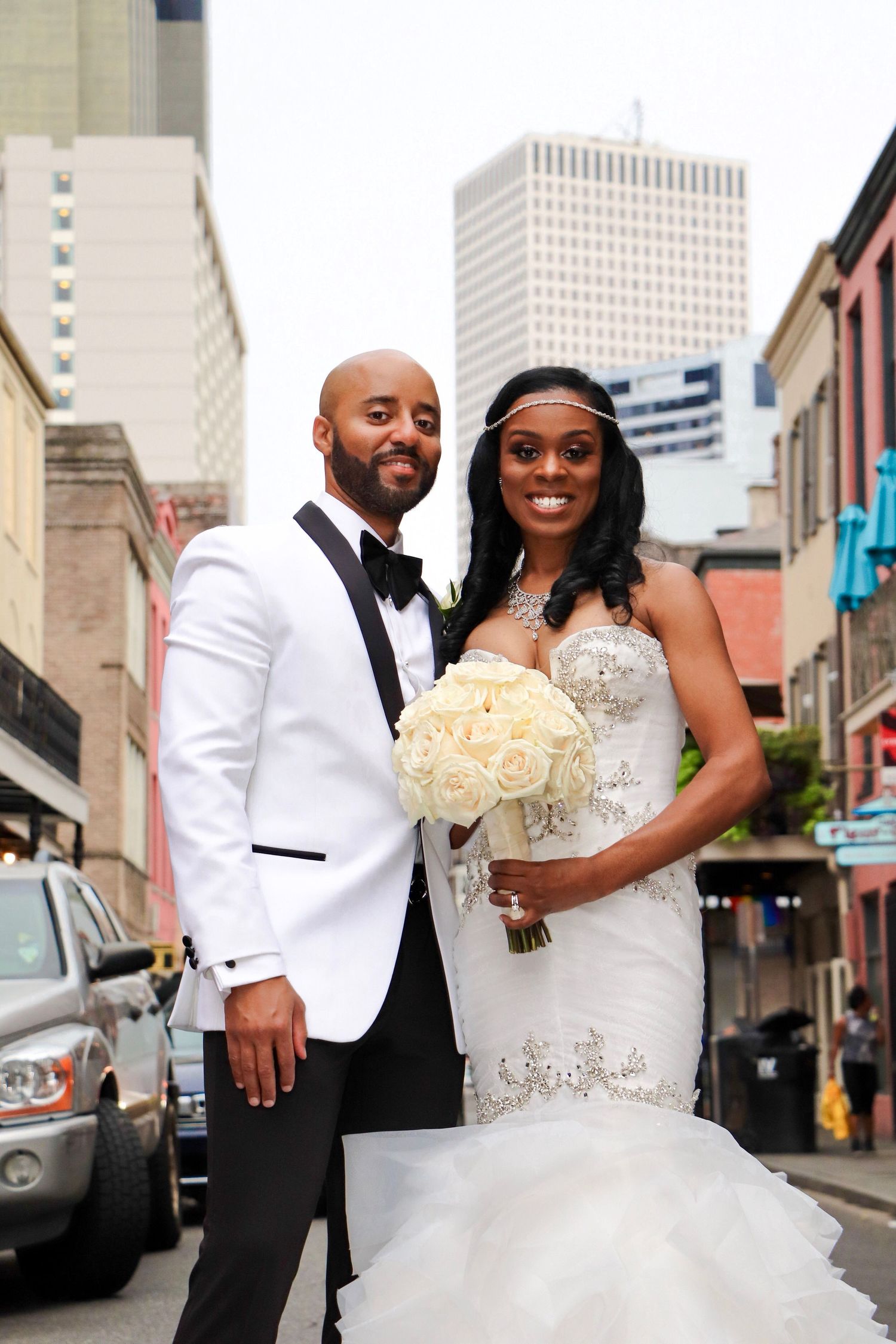 Newlyweds pose for portrait on urban street with cityscape backdrop.