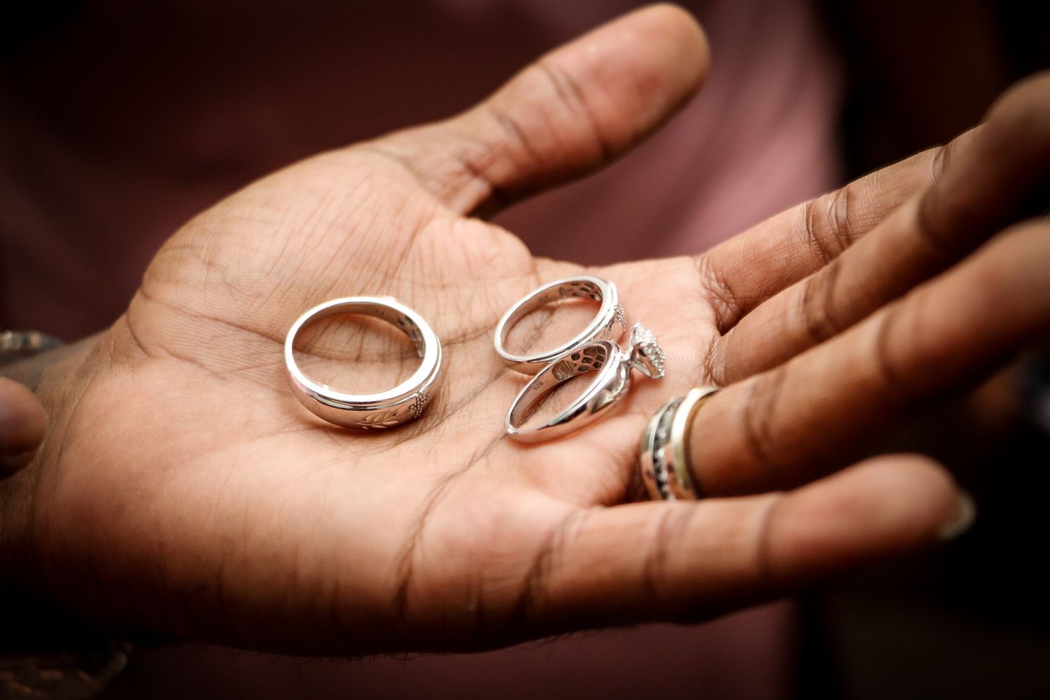Several silver wedding rings rest in an open palm showing various styles and designs.