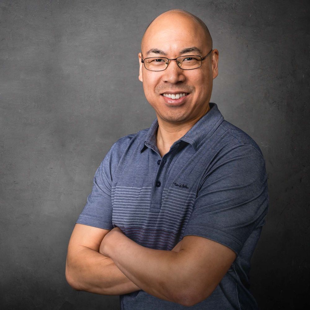 Professional headshot of a smiling business man with glasses gray photography studio background