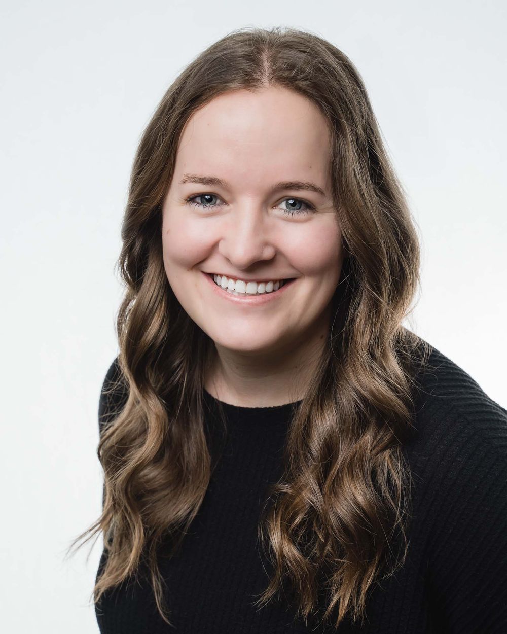 Professional headshot of a smiling woman with white photography studio background