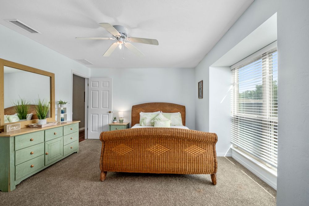 A small bedroom with a sleigh bed and green dresser.