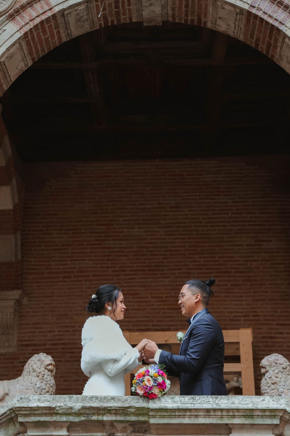 A couple shares a tender moment on a balcony during their wedding ceremony.