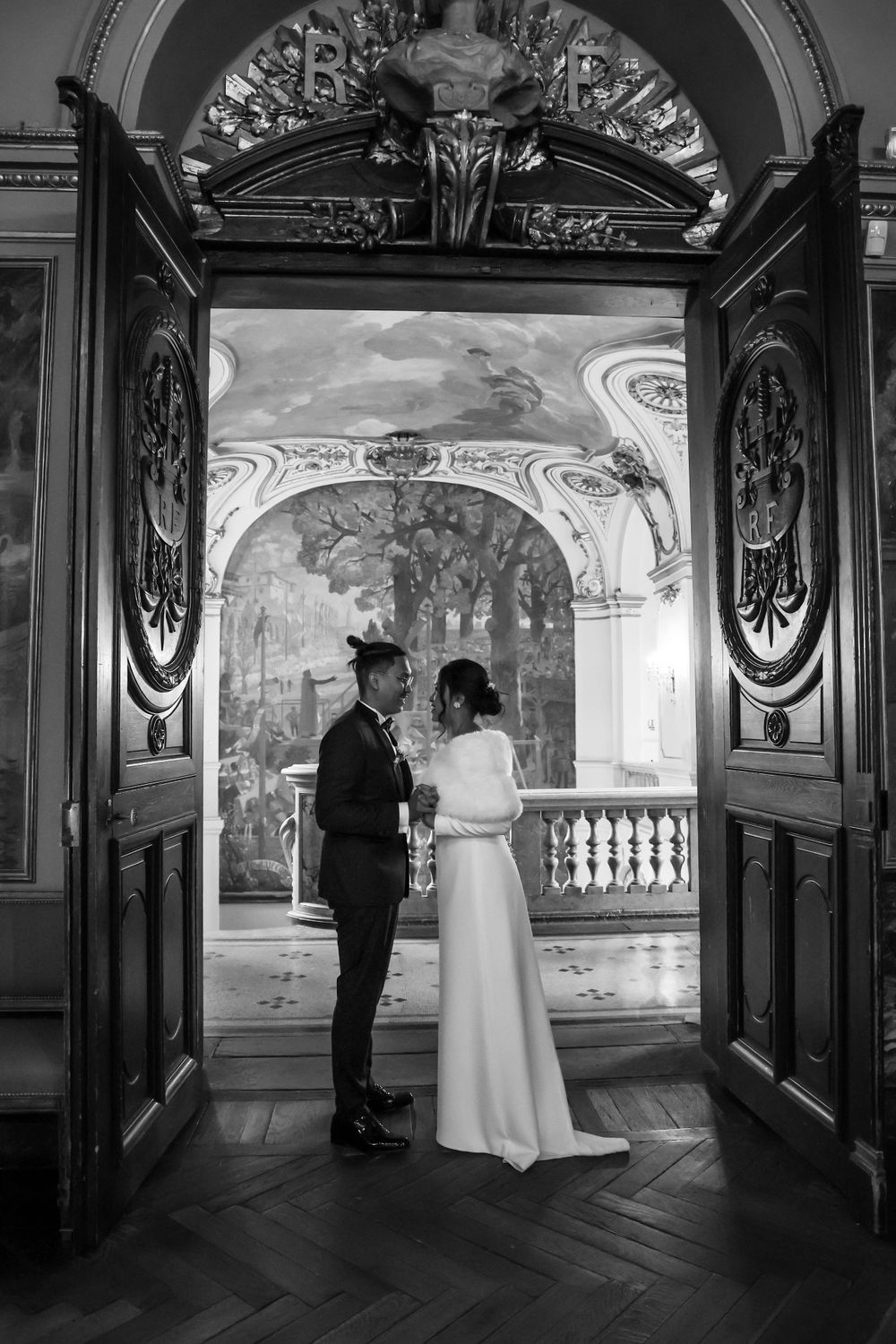 A black and white photo of a couple standing in an ornate doorway with carved details.
