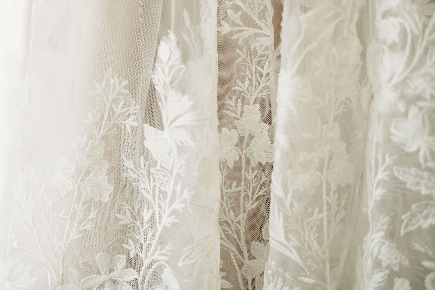 Delicate floral lace pattern on sheer white wedding dress fabric.