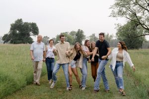 Sioux City, Iowa photographer. Large family group walking and laughing together in a lush green meadow.