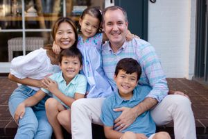 Sioux City, Iowa photographer. Smiling blended family of five in coordinating outfits posing together on outdoor steps for portrait photo.