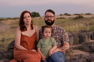 Sioux City, Iowa photographer. Young family portrait with parents and toddler sitting on rocks in natural outdoor setting at dusk.