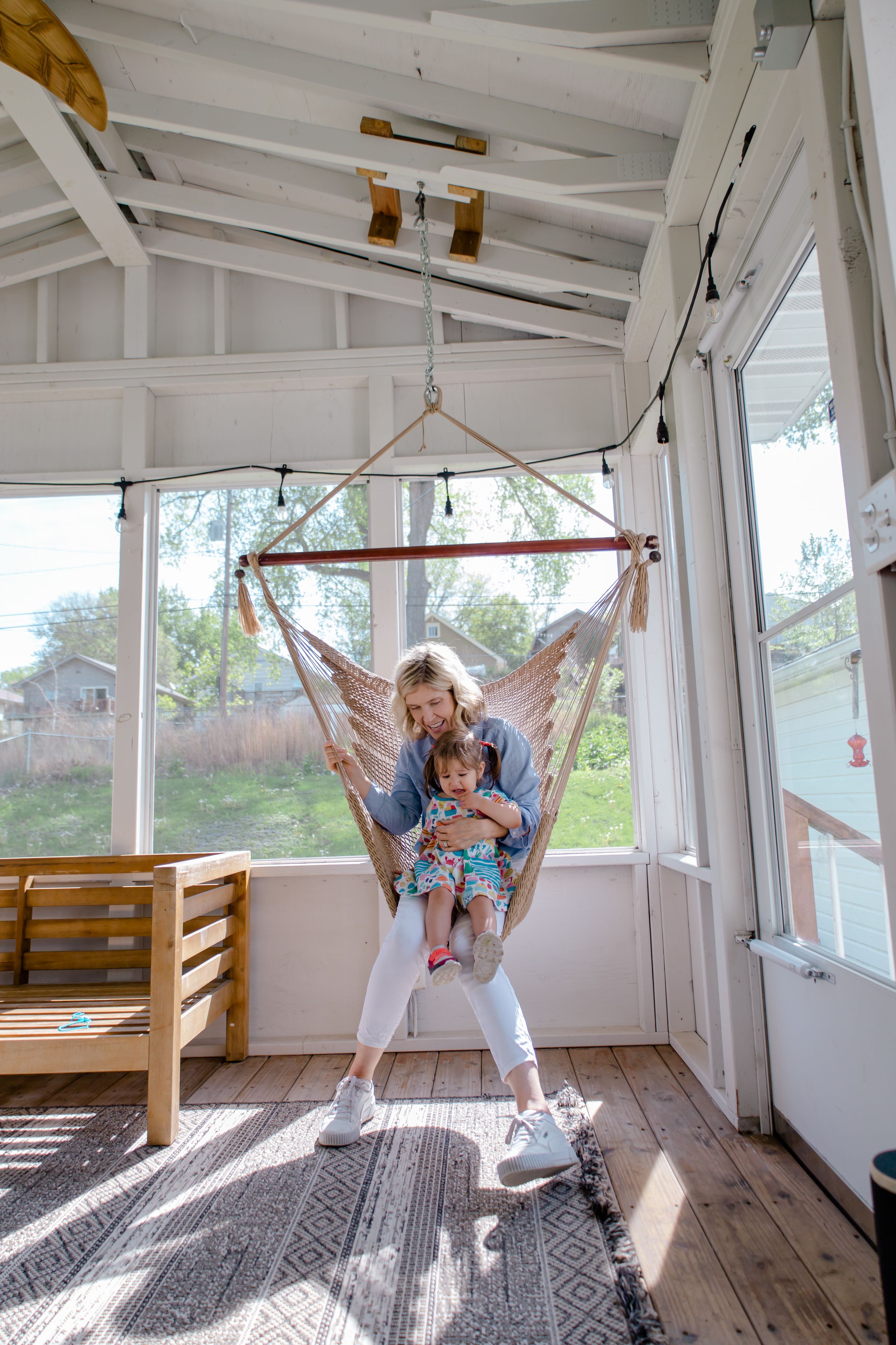 Sioux City, Iowa photographer. grandmother and toddler sitting together in a hanging hammock chair on a bright sunlit porch.