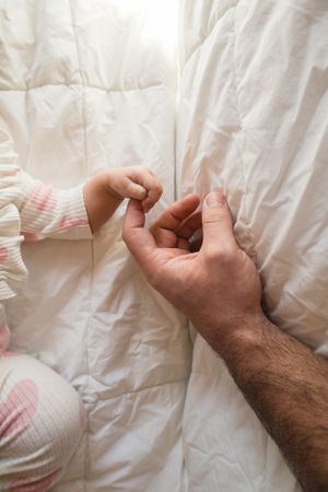 Sioux City, Iowa photographer. A baby's tiny hand gently gripping an adult's finger on a white quilted blanket.
