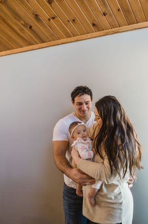 Sioux City, Iowa photographer. Happy young parents smiling at their newborn baby in a modern wooden ceiling room.
