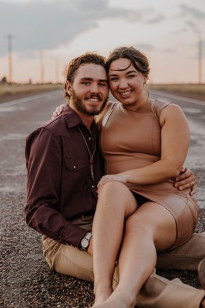 Couple sitting together on ground during sunset photoshoot.