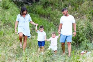 Family walking together on a grassy hillside path during summer.