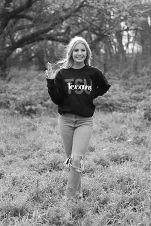Black and white portrait of person in Texas sweatshirt standing in nature.