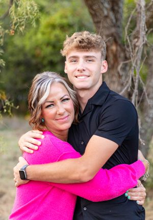 A warm embrace shared outdoors with greenery in the background.