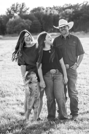 Black and white portrait of a casual country family enjoying a candid moment together in a field.