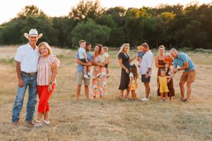 Family and friends posing together in a rustic outdoor field setting during golden hour.