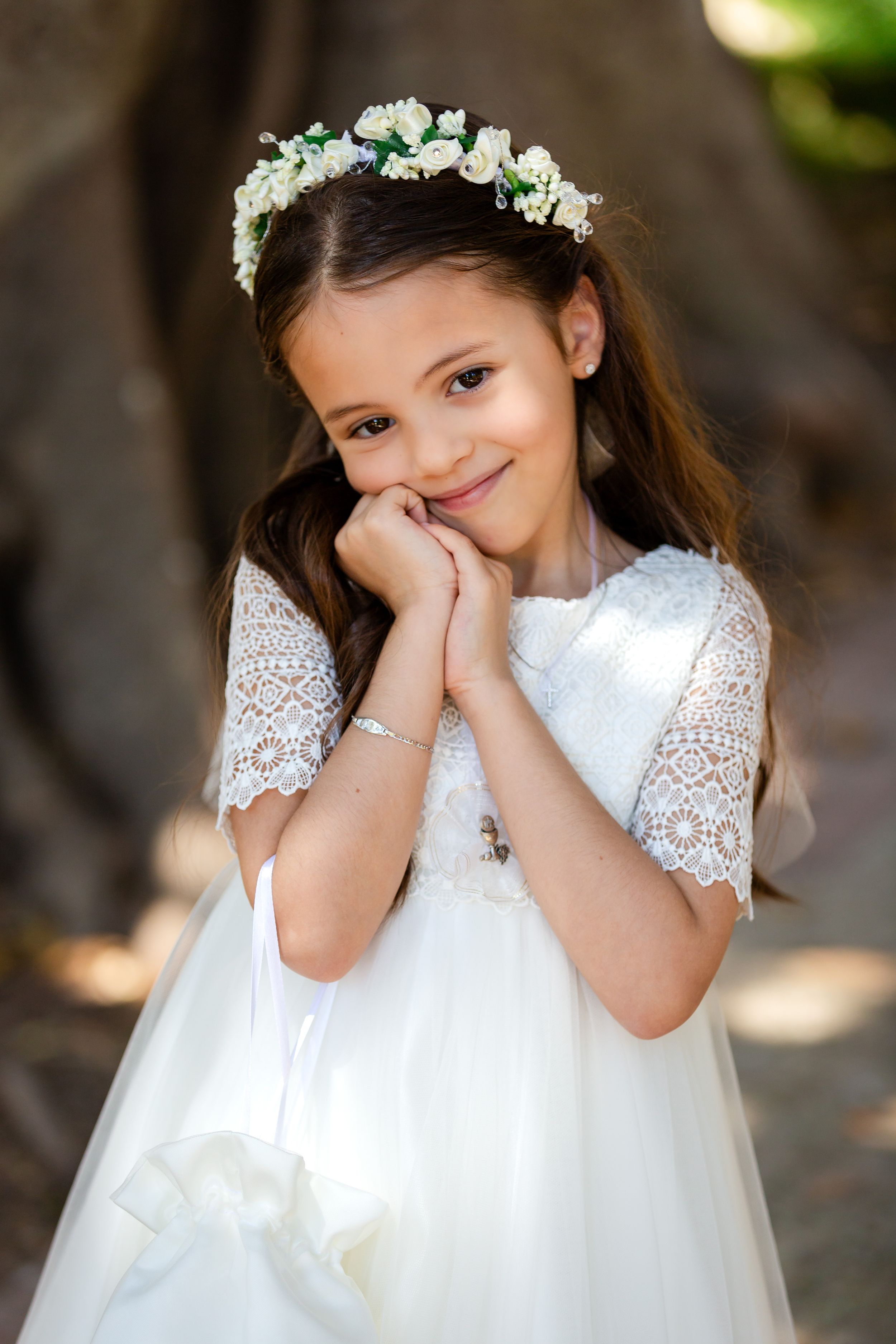 White lace dress and floral crown create an enchanting portrait in natural light.