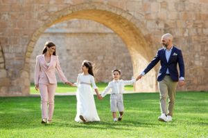 Family relaxes together under stone archways in garden setting.