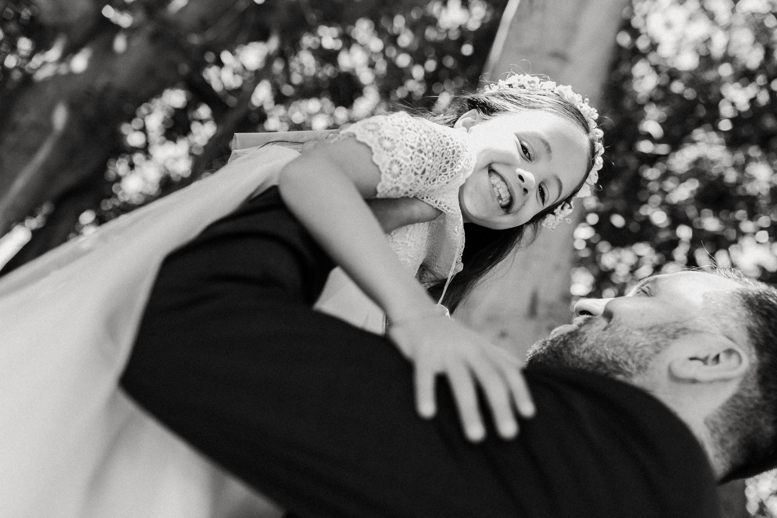 Black and white portrait captures a joyful moment in a garden setting.