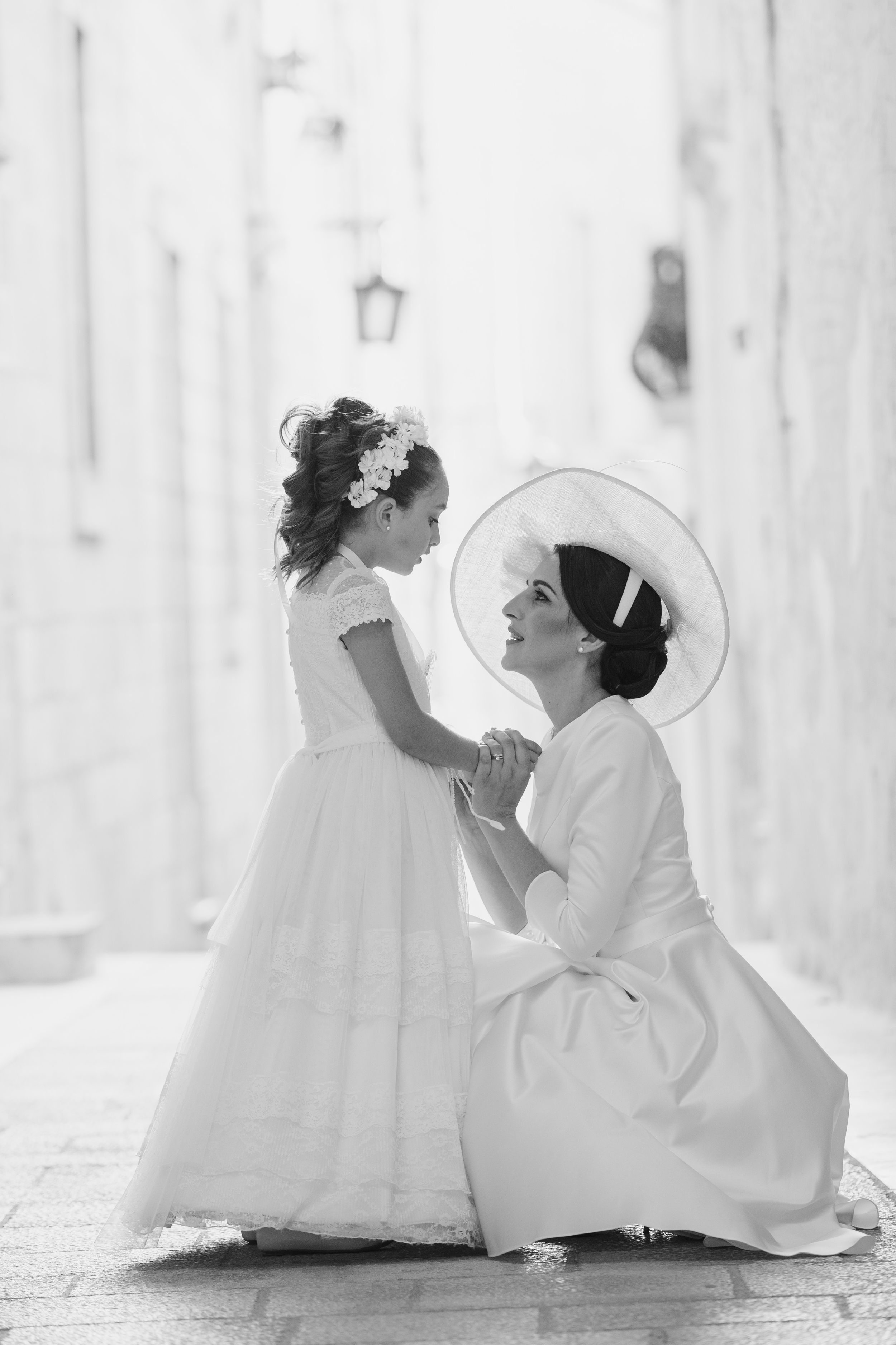Two figures in white dresses sit on the ground creating artistic wedding portraits.