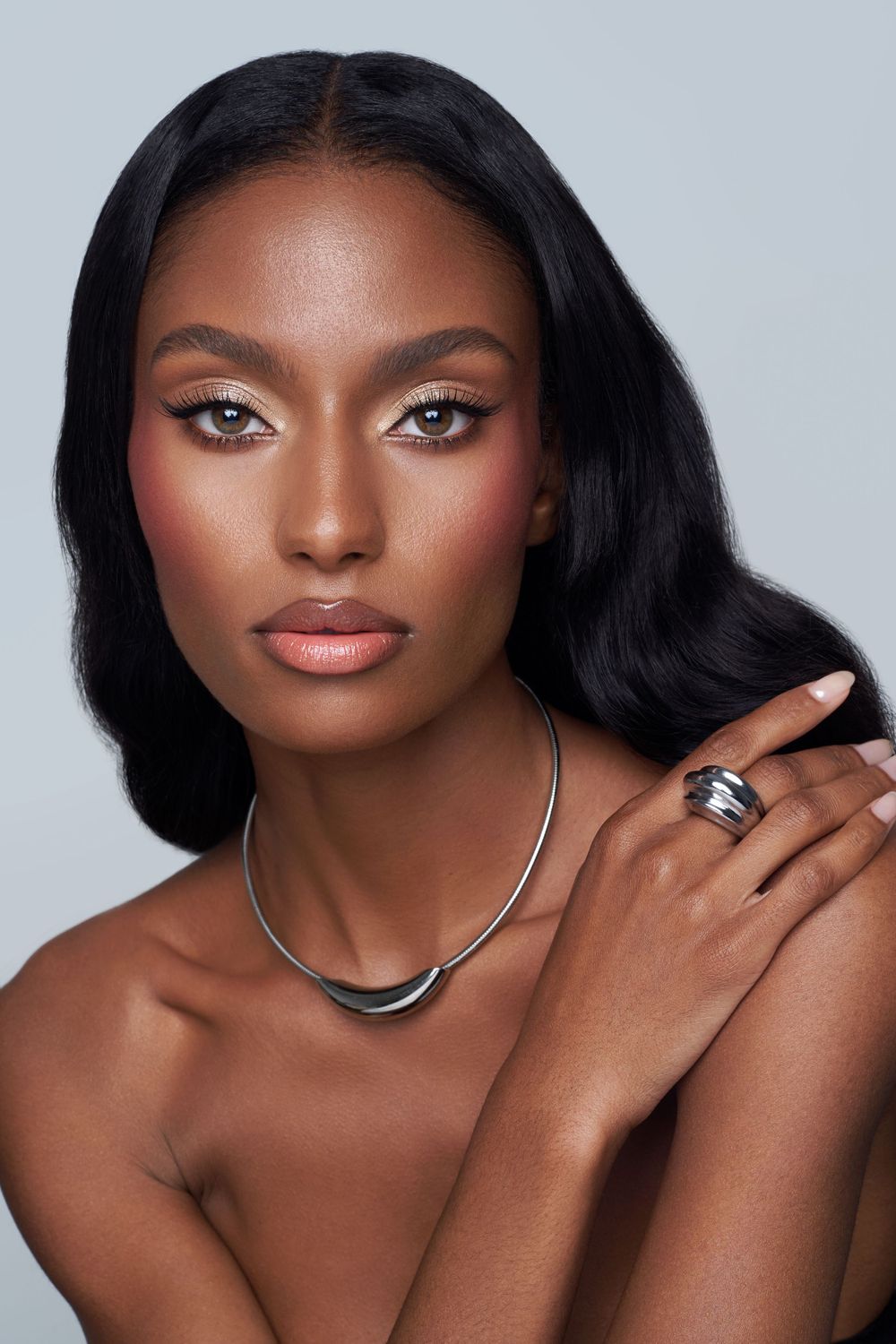 Elegant beauty portrait with silver necklace, flawless makeup and wavy dark hair.