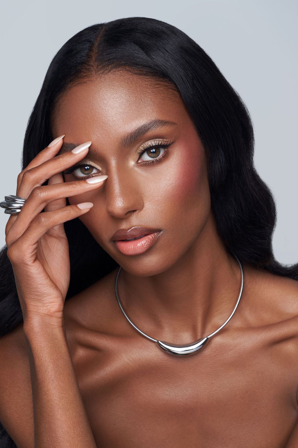 Glamorous beauty shot with silver jewelry, dramatic makeup and flowing dark hair.