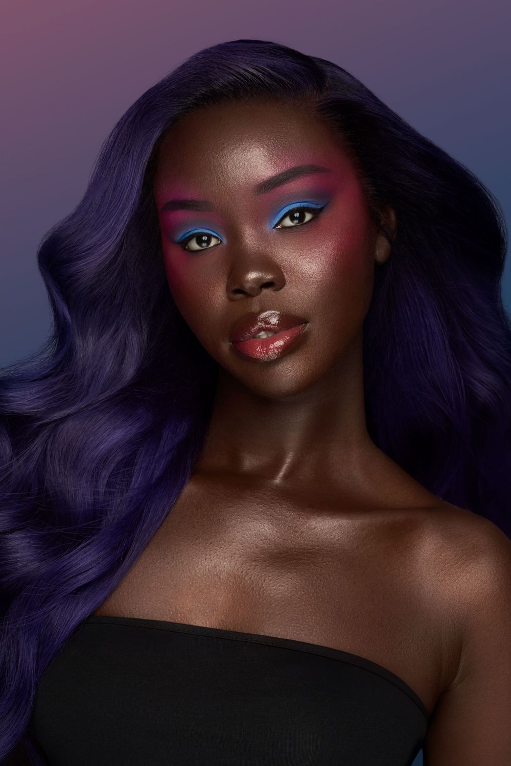 Artistic beauty shot with vibrant purple hair and colorful eye makeup.