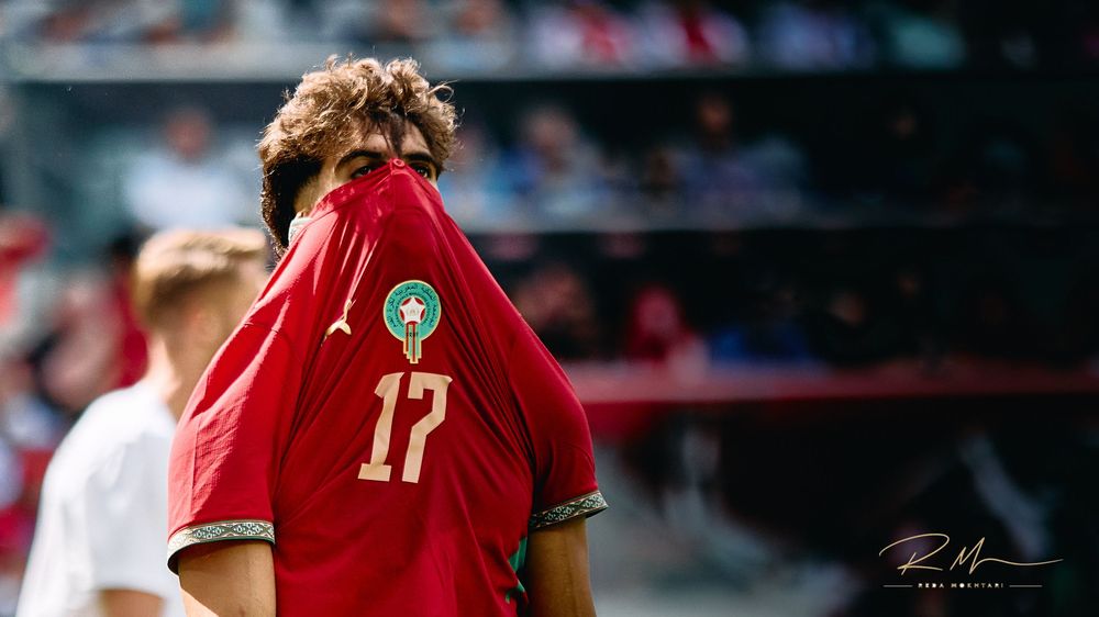 Morocco soccer player #17 pulling red jersey over face after match.