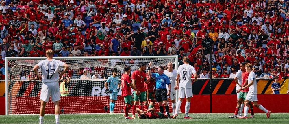 Portugal soccer players celebrate a goal during an international match with a packed stadium of fans in the background.