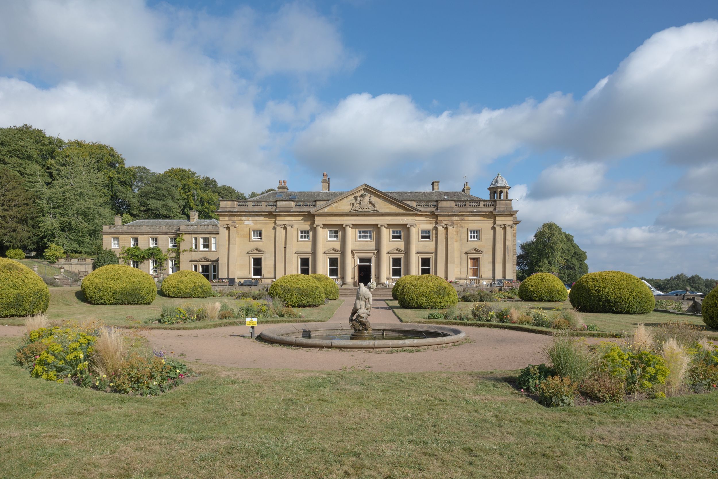 Elegant English country manor house Wortley Hall Sheffield, manicured gardens and circular driveway featuring ornate fountain centerpiece.