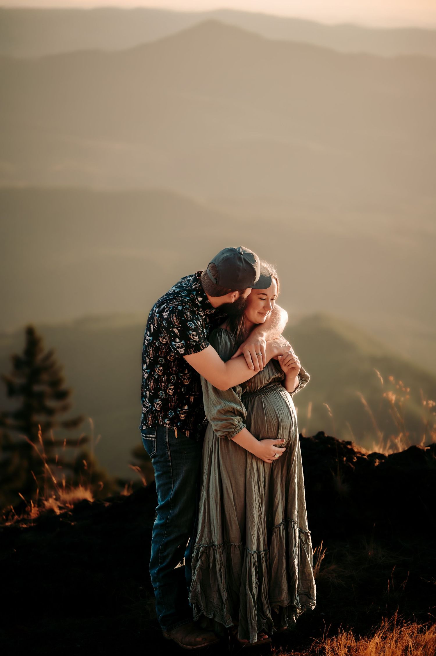 Sunset mountain engagement photo with couple embracing in soft light.