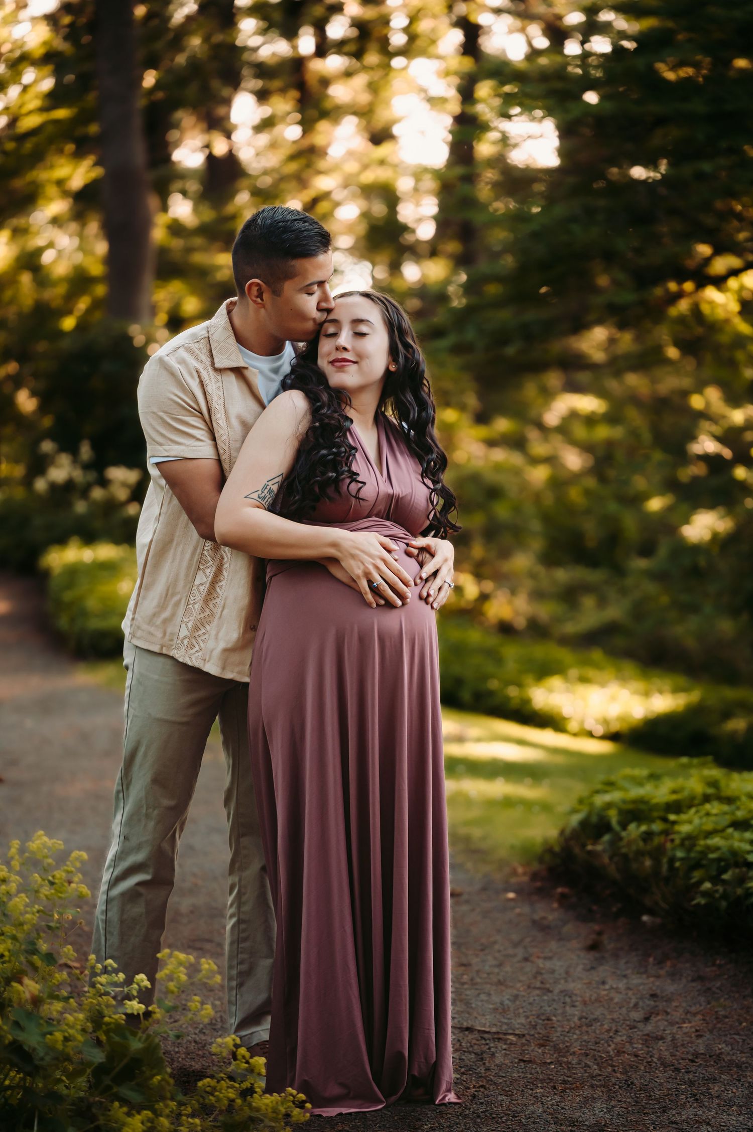 Intimate maternity photoshoot in a wooded setting during golden hour.