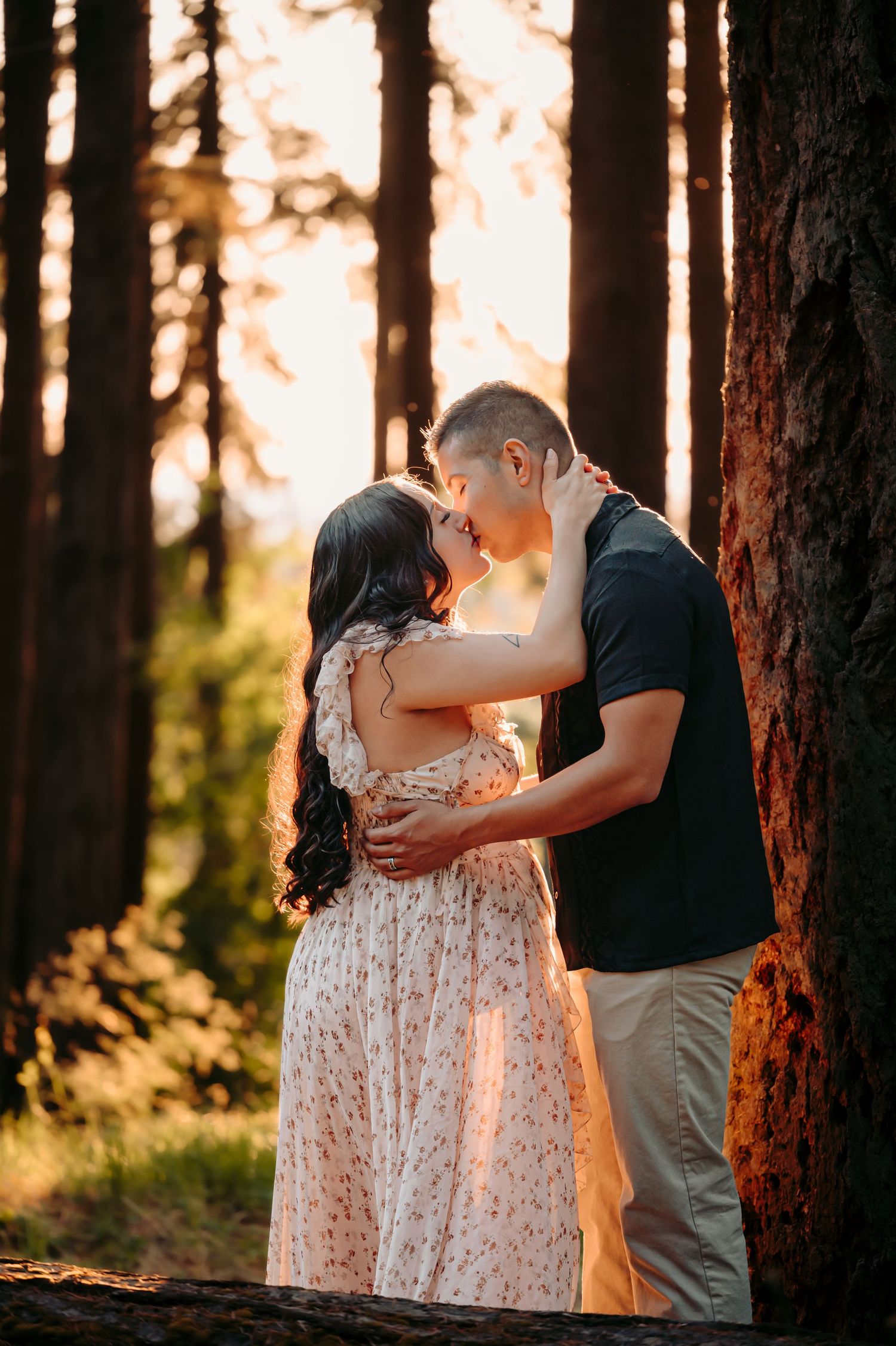 Romantic forest photoshoot with couple in floral dress and casual wear at sunset.